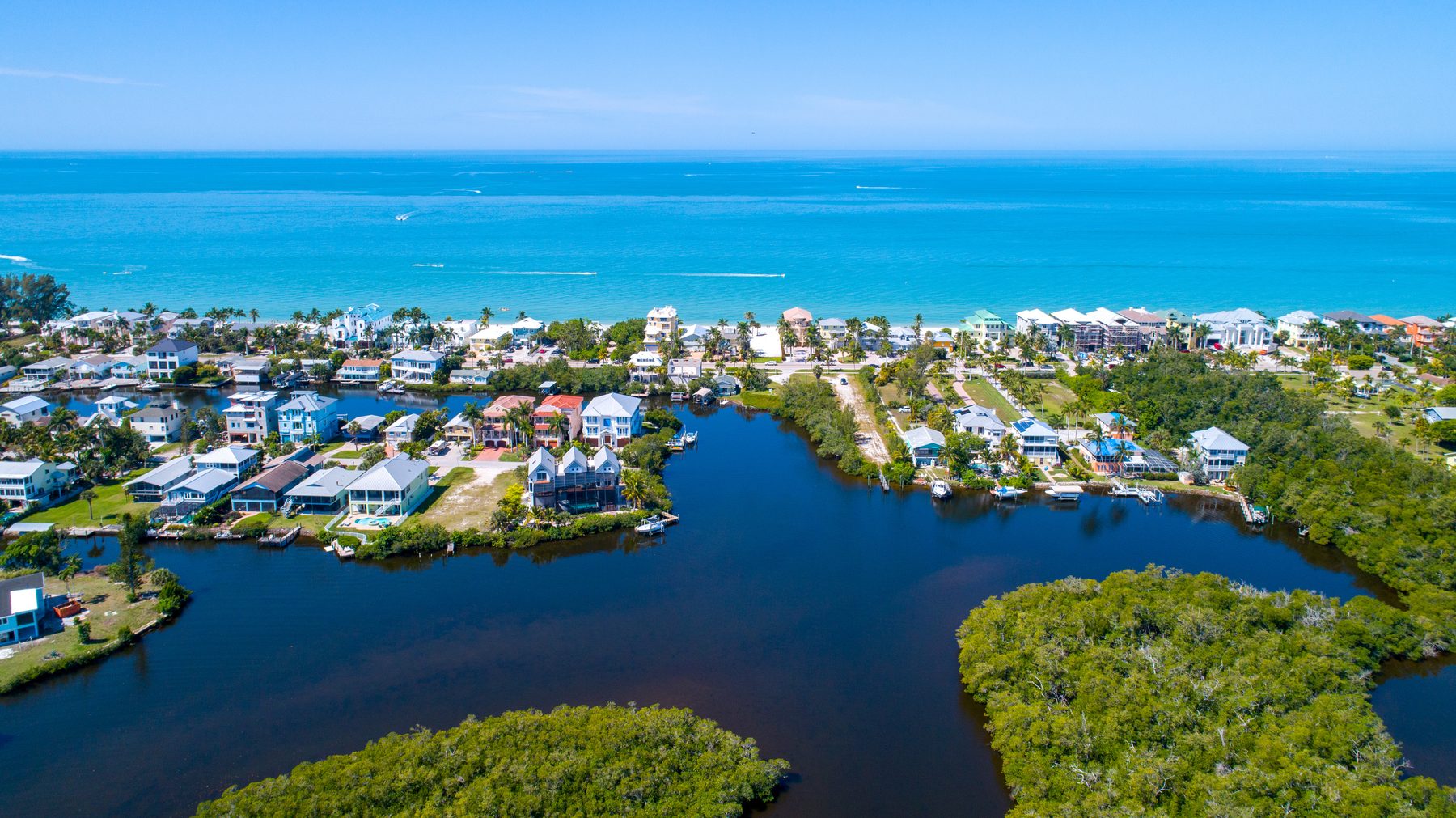 Aerial view of a canal-front community with Gulf beach in the background