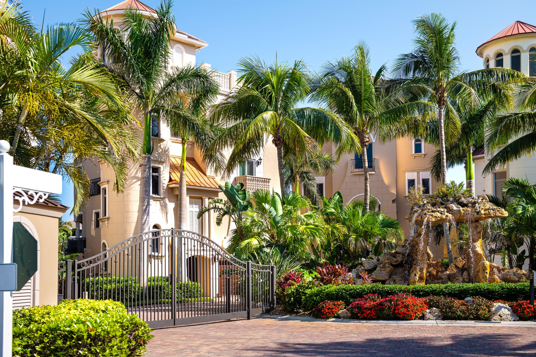 Gated entrance to a Southwest Florida luxury community with a fountain and palms